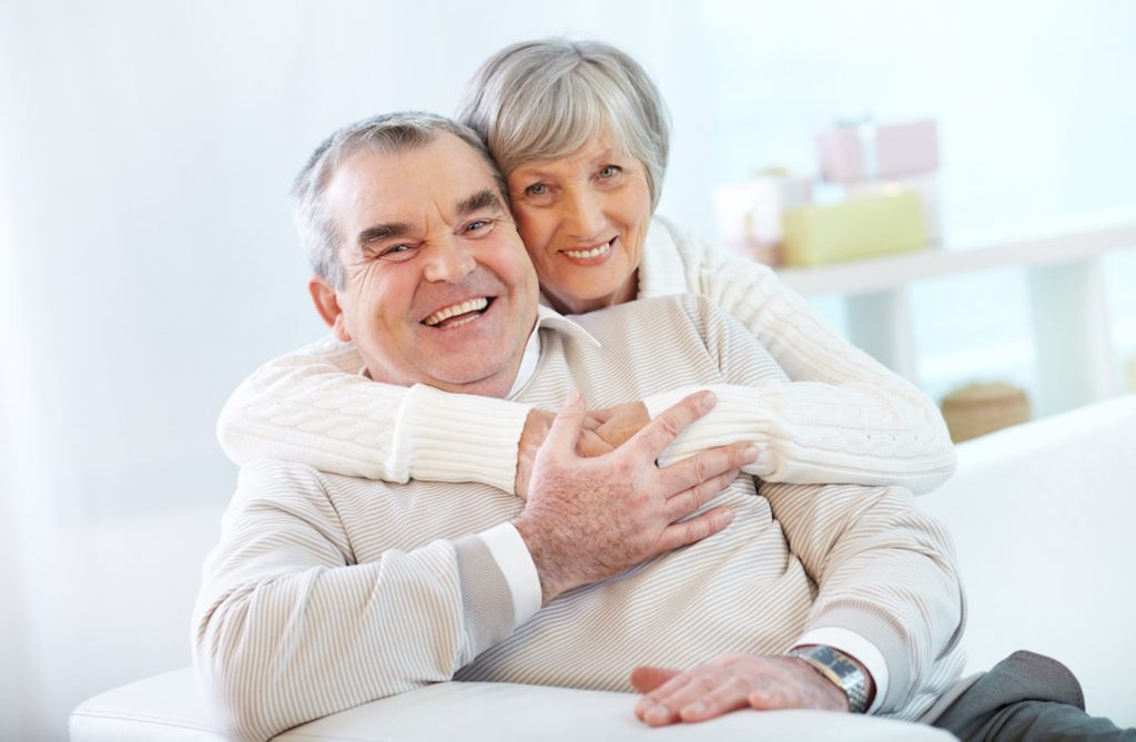 Portrait of a happy senior woman embracing her husband and both looking at camera